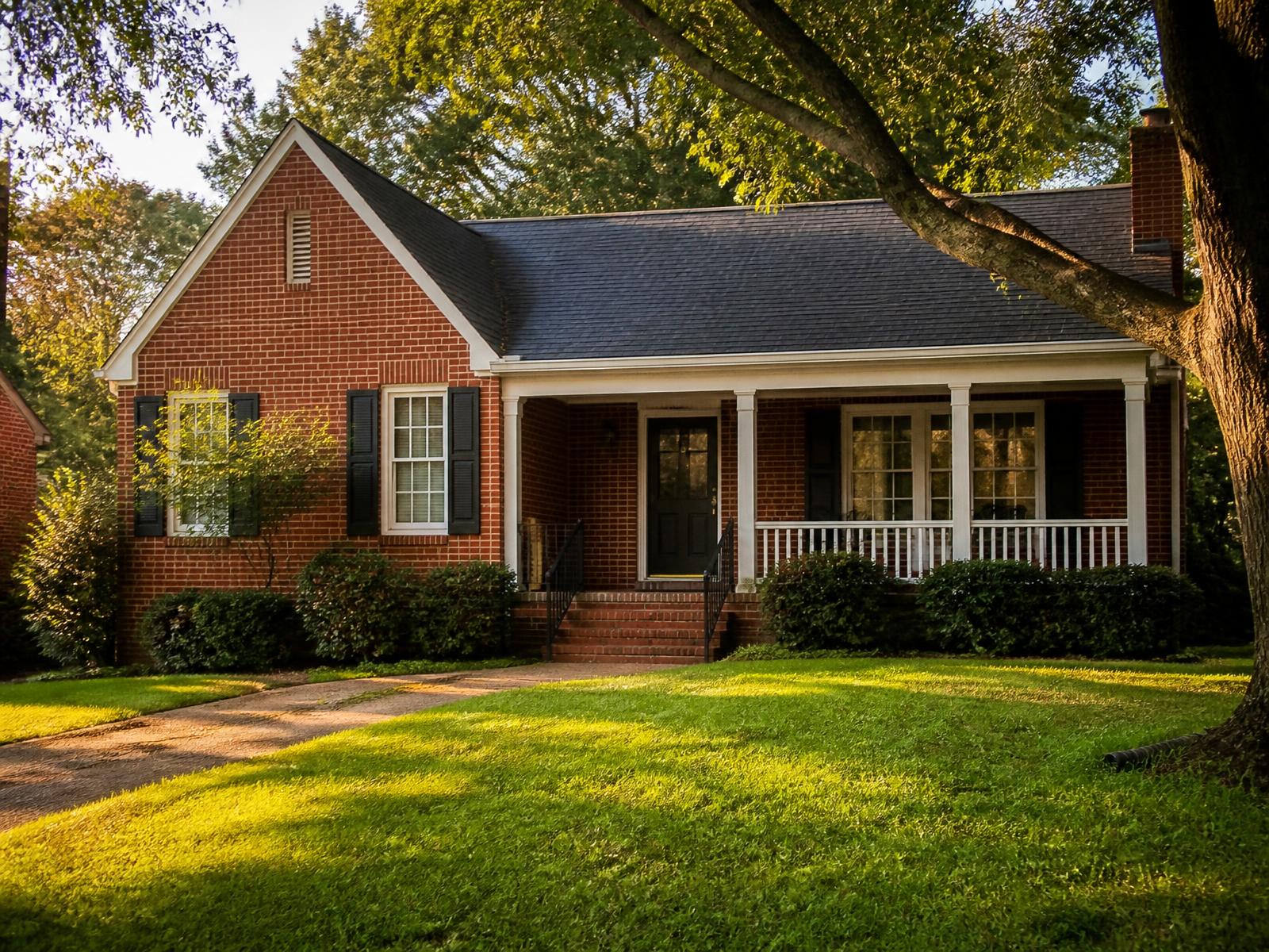 A brick single-family home on a tree-lined Memphis street in late afternoon light